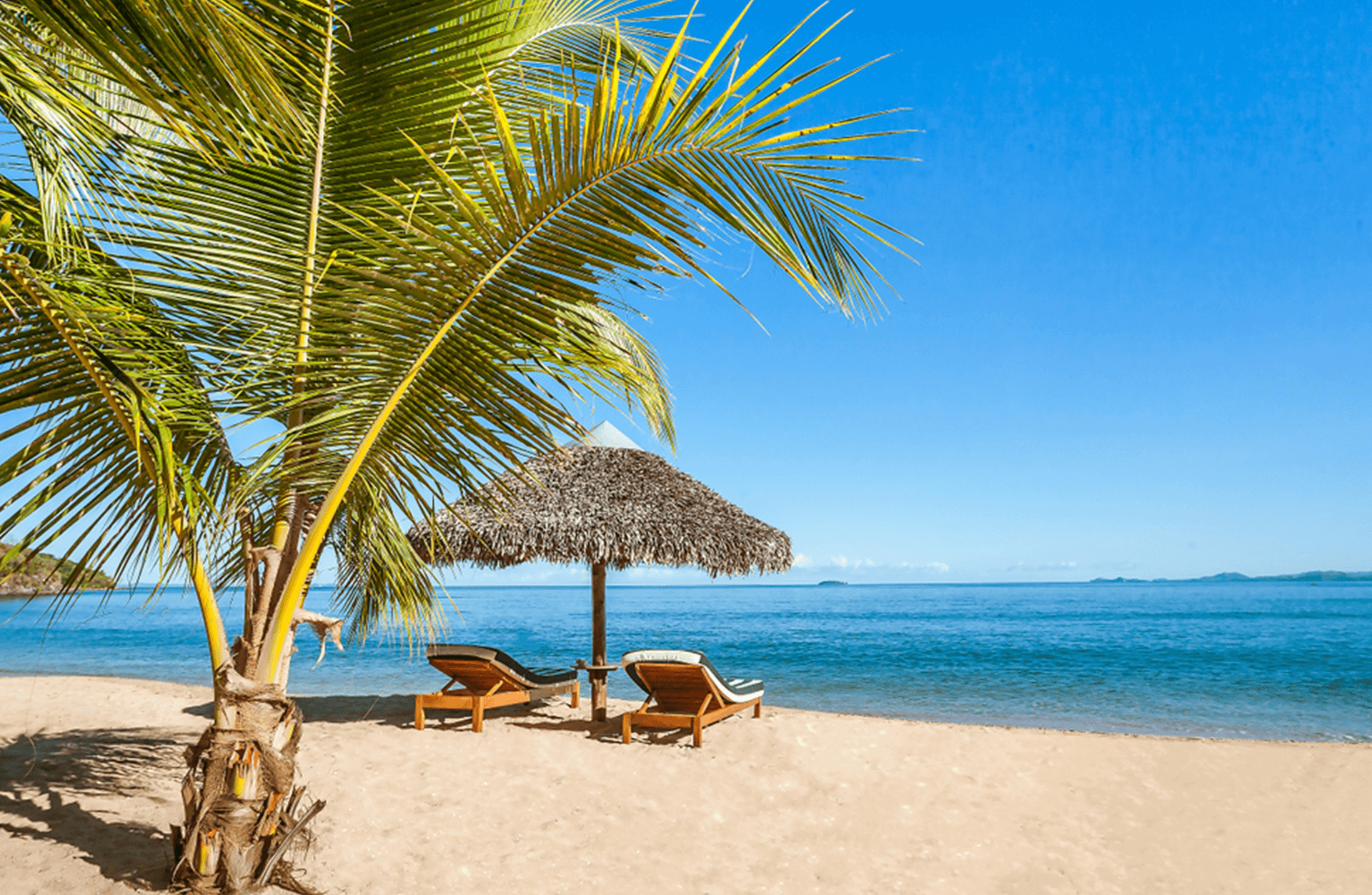 Two sunbeds under straw umbrella